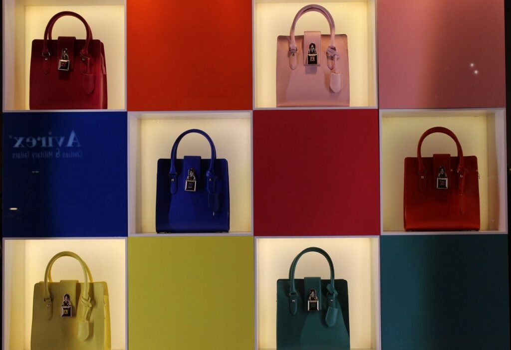 A vibrant display of handbags arranged on multicolored panels in a fashion store.